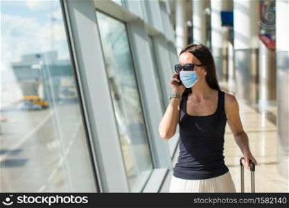 Woman wearing a mask for prevent virus with baggage in international airport. Protection against Coronavirus and gripp. Young tourist woman with baggage in international airport
