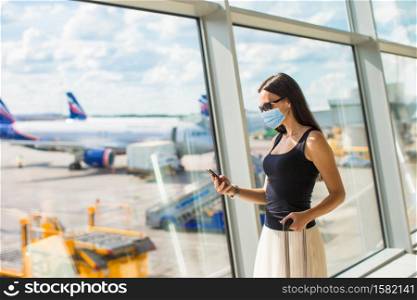 Woman wearing a mask for prevent virus with baggage in international airport. Protection against Coronavirus and gripp. Young tourist woman with baggage in international airport