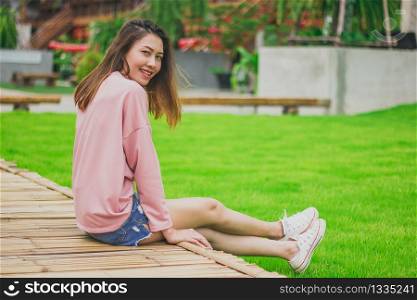 Woman wearing a pink shirt sitting on a bamboo bridge.