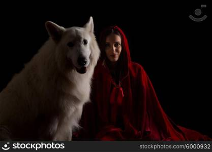 Woman wearing a red hood posing in studio with her dog