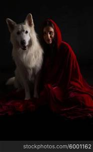 Woman wearing a red hood posing in studio with her dog