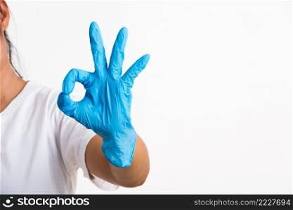 Woman wearing and putting hand to blue rubber latex glove for doctor with OK sign gesturing, studio shot isolated on white background, Hospital medical safety concept