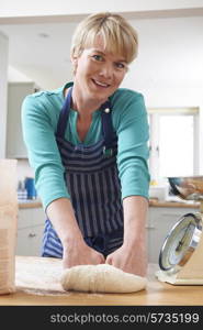 Woman Wearing Apron And Kneading Dough In Kitchen