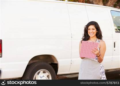Woman Wearing Apron With Clipboard In Front Of Van