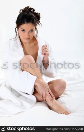 Woman wearing bathing-gown sat on bed