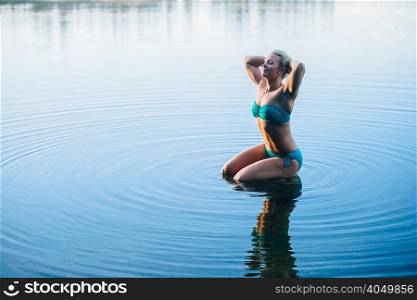Woman wearing bikini kneeling in water
