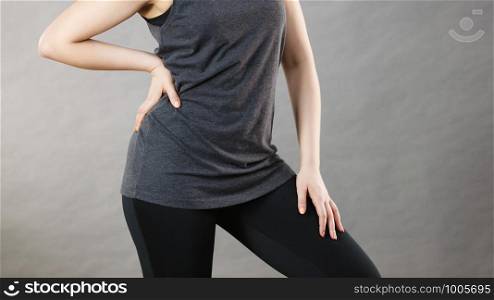 Woman wearing black tank top and leggings. Sporty outfit. Studio shot on grey background.. Woman wearing black tank top