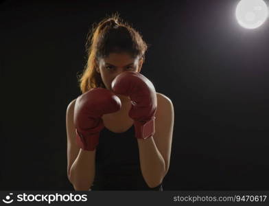 Woman wearing boxing gloves ready to throw a punch. 