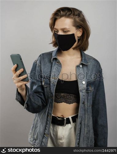 woman wearing denim jacket mask while using mobile