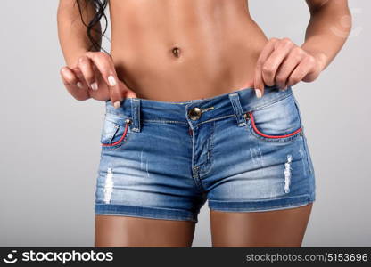 Woman wearing denim shorts with a beautiful waist. Studio shot