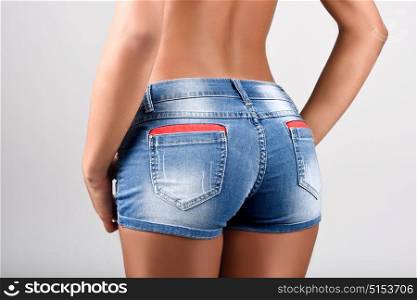 Woman wearing denim shorts with a beautiful waist. Studio shot