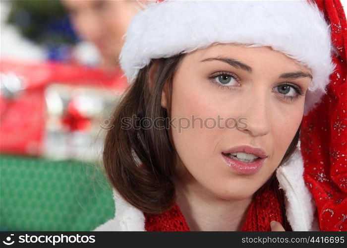 Woman wearing festive hat stood in front of presents