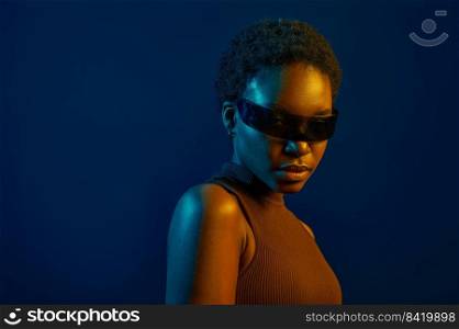 Woman wearing futuristic eyeglasses in neon light over dark studio background. Woman in futuristic eyeglasses over dark studio background