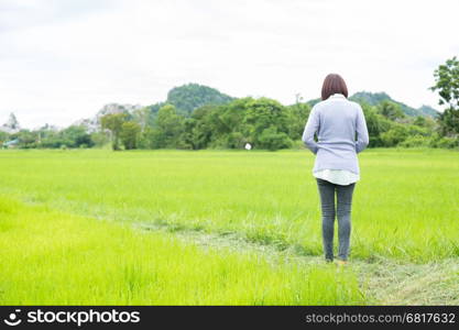 Woman wearing glasses, standing in a rice field in nature.