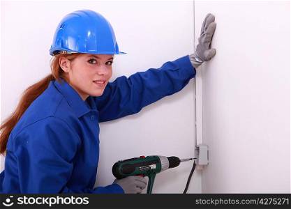 Woman wearing gloves whilst using power drill