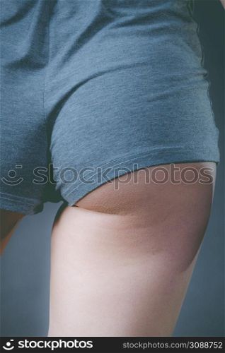 Woman wearing grey shorts showing her buttock. Feminine curves, slim sporty body shape.. Woman wearing grey shorts showing her buttock.