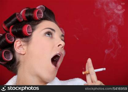 Woman wearing hair-rollers smoking