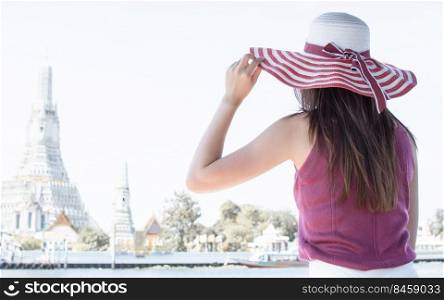 Woman wearing hat and sitting near river with background of beautiful landscape. Lifestyle and Travel Concept.
