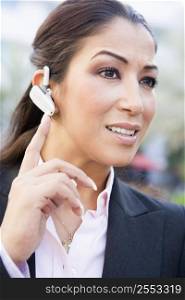 Woman wearing headset outdoors smiling (selective focus)
