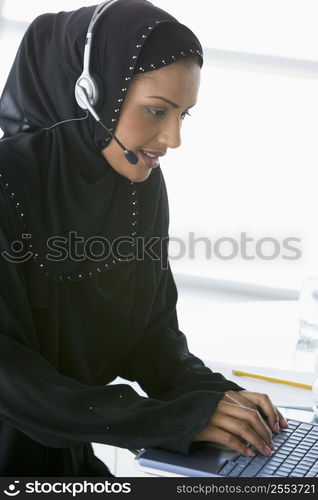 Woman wearing headset with laptop smiling (high key/selective focus)