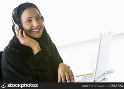 Woman wearing headset with laptop smiling (high key/selective focus)