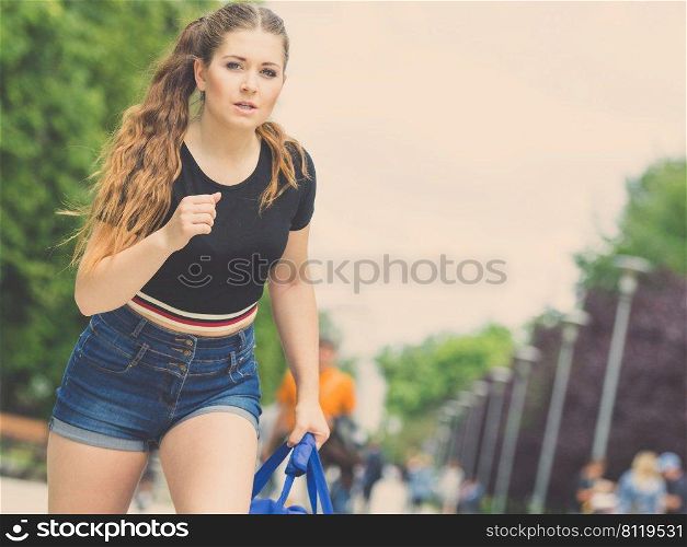 Woman wearing jeans denim shorts running somewhere in town being late during summer weather.. Teenage woman running late outdoor.