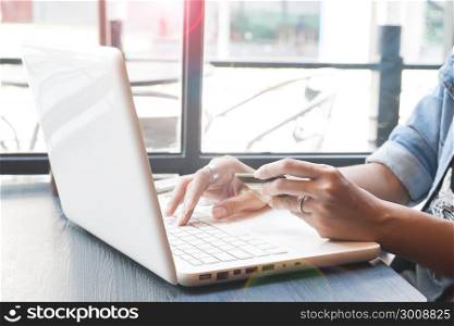 Woman wearing jeans jacket using laptop computer in cafe, Online shopping concept