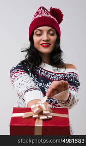 Woman wearing knitted winter dress and hat holding and opening Christmas gift