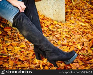 Woman wearing long black heeled knee high boots and jeans. Autumn fashion, warm footwear boots.. Woman wearing black knee high boots