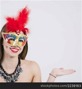 woman wearing masquerade carnival mask necklace gesturing white backdrop