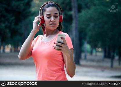 woman wearing music helmets and using her mobile in a park