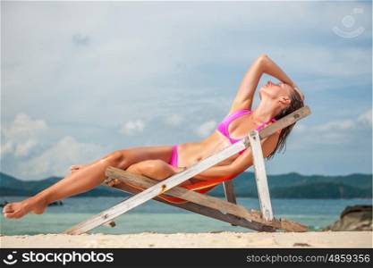 Woman wearing pink bikini in lounger on tropical beach at Thailand