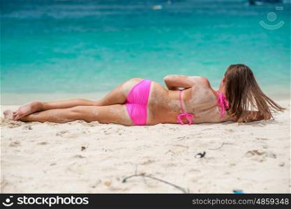 Woman wearing pink bikini laying on tropical beach at Thailand