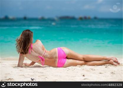 Woman wearing pink bikini laying on tropical beach at Thailand