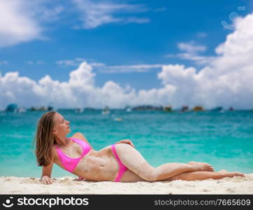 Woman wearing pink bikini laying on tropical beach at Thailand