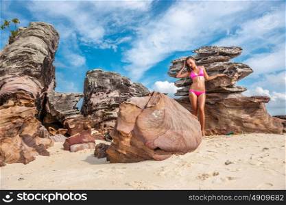 Woman wearing pink bikini on a rocky beach in Thailand