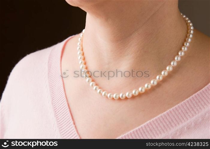 Woman wearing real pearls and pink sweater.