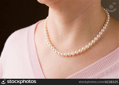 Woman wearing real pearls and pink sweater.