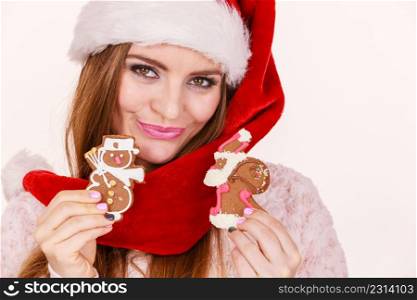 Woman wearing red hat holding delicious sweet gingerbread xmas cookies little snowman and santa claus. Happy girl awaiting christmas holidays. Woman santa claus hat with gingerbread cookies. Christmas