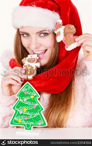 Woman wearing red xmas hat playing with gingerbread cookies little snowman and claus. Happy girl awaiting christmas holidays. Woman santa claus hat with gingerbread cookies. Christmas