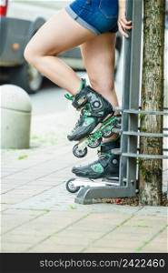 Woman wearing roller skates sitting in town. Female being sporty during summer time.. Woman wearing roller skates