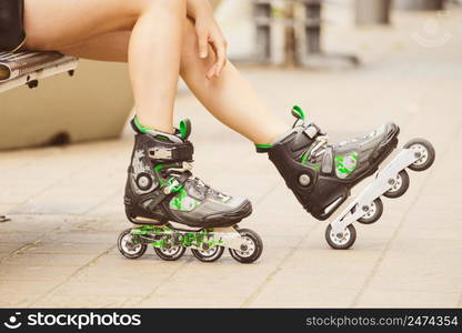 Woman wearing roller skates sitting in town. Female being sporty during summer time.. Woman wearing roller skates