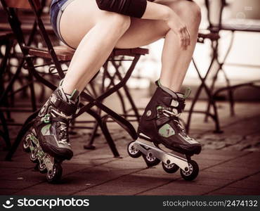 Woman wearing roller skates sitting in town. Female being sporty having fun during summer time.. Woman riding roller skates