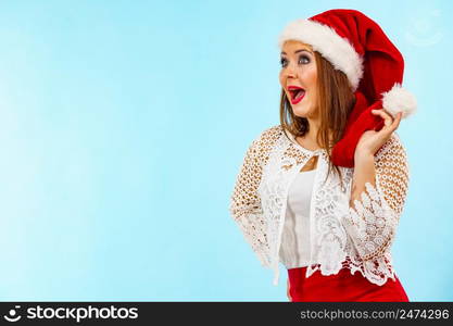 Woman wearing santa claus hat surprised shocked face expression, on blue. Christmes time.. Shocked santa claus christmas woman