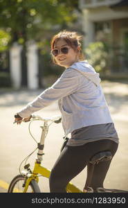 woman wearing sport clothes toothy smiling face on mini bicycle