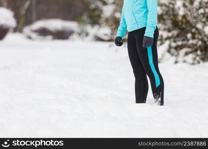 Woman wearing sportswear and running on snow with trees in background, no face. Winter sports, outdoor fitness, workout, health concept.. Running lady legs, sporty clothes, winter fitness