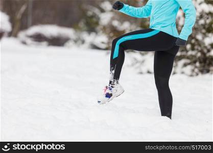 Woman wearing sportswear and running on snow with trees in background, no face. Winter sports, outdoor fitness, workout, health concept.. Running lady legs, sporty clothes, winter fitness