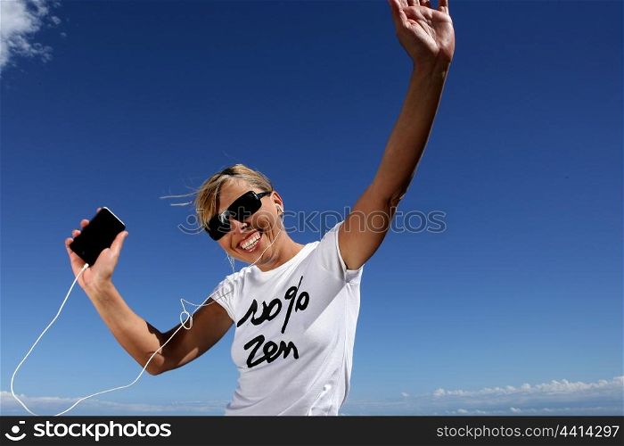 Woman wearing sunglasses listening to music through digital player
