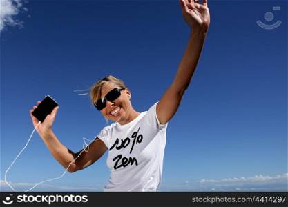 Woman wearing sunglasses listening to music through digital player