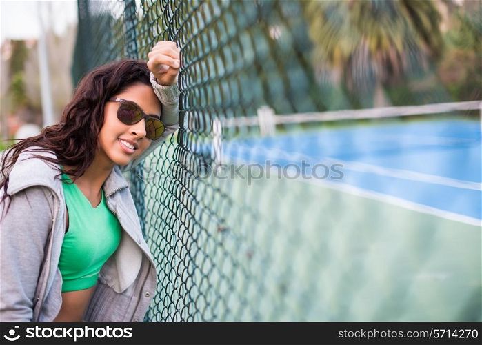Woman wearing sunglasses over tennis court background